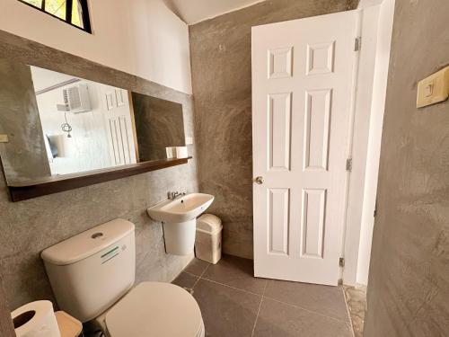 un bagno con un water, un lavandino e uno specchio di Villa Milagros Dive Inn Anilao a Bagalañgit