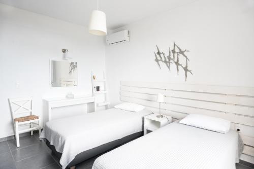 two beds in a room with white walls at Aegean Breeze Skiathos in Skiathos Town