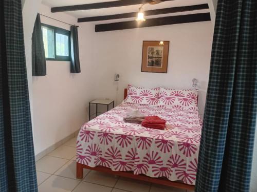 a bedroom with a bed with a pink and white comforter at Landhaus Samaipata in Samaipata