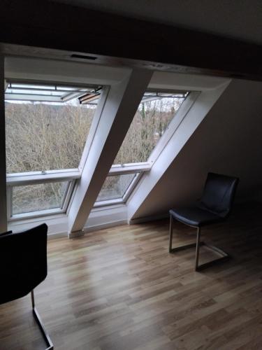 a room with two windows and a chair in it at Artemis in Wissembourg