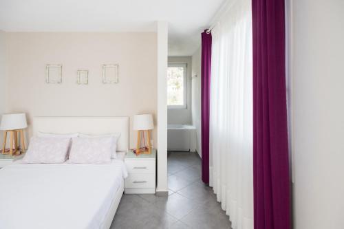 a bedroom with a white bed and purple curtains at Aegean Breeze Skiathos in Skiathos Town