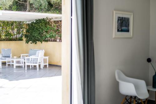 a view of a patio with white chairs and a table at Aegean Breeze Skiathos in Skiathos Town