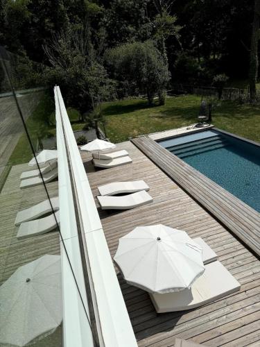 une terrasse en bois avec parasols et une piscine dans l'établissement Villa Brisson, à Léognan