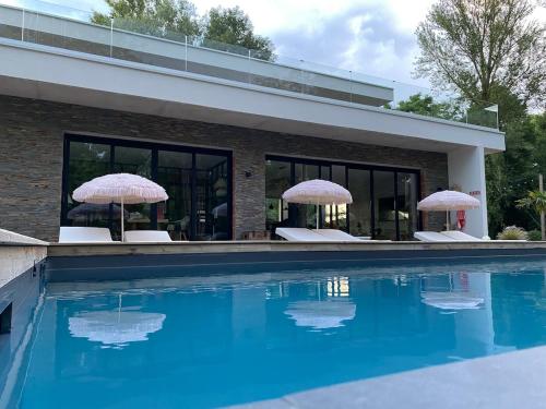 une maison avec deux parasols et une piscine dans l'établissement Villa Brisson, à Léognan