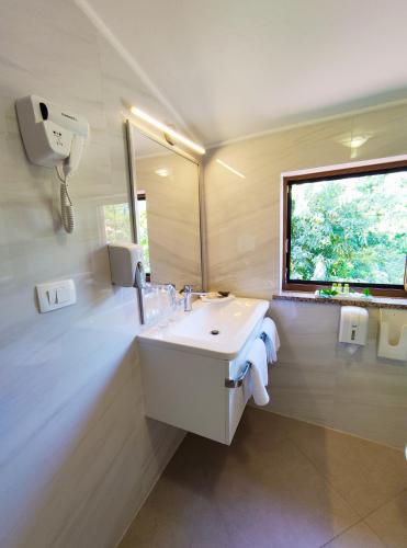 a white bathroom with a sink and a window at Pansion Comfort Santa Marija in Novigrad Istria
