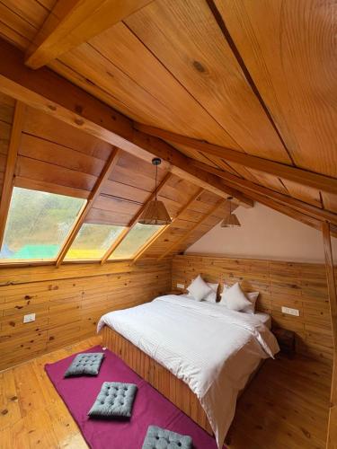 a bedroom with a bed in a wooden ceiling at Naddi Pine Wood Hut in Dharamshala