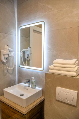 a bathroom with a sink and a mirror and towels at Vila sa bazenom Vrnjačka Idila in Vrnjačka Banja