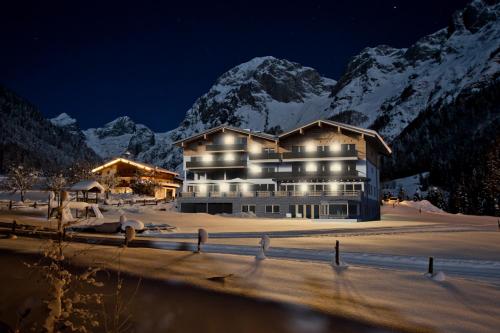 a large building with snowy mountains in the background at Berghotel Lämmerhof in Sankt Martin am Tennengebirge