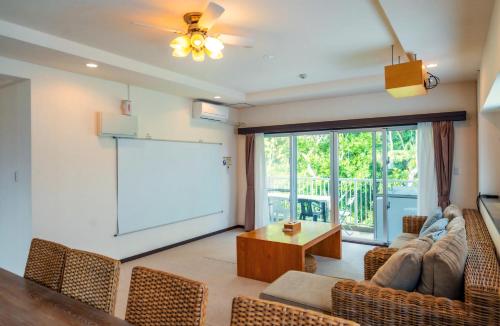 a living room with a white screen and a couch at Scallop Beach Condominium in Onna