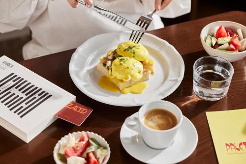 a table with a plate of food and a cup of coffee at Hotel Bazaar - Fattal Colors in Tel Aviv