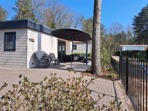 a house with a table and an umbrella at Boshuisje op de Schatberg in Sevenum