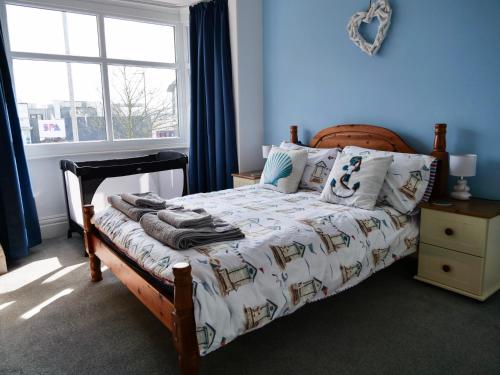 a bedroom with a bed with blue walls and a window at Seashells in Bridlington