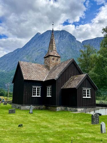 a church in a field with mountains in the background at Bispen Villa Utsikten in Åndalsnes