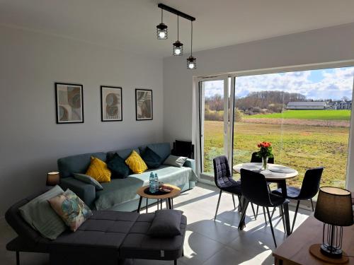 a living room with a couch and a table with chairs at Apartament Szczęśliwy - 14 in Ustronie Morskie