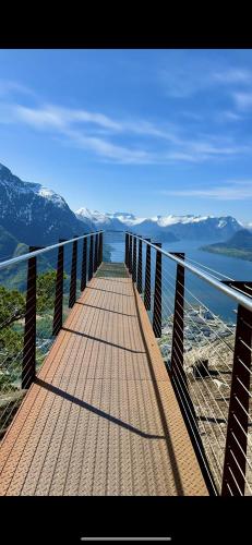 a wooden bridge with a view of the water and mountains at Bispen Villa Utsikten in Åndalsnes