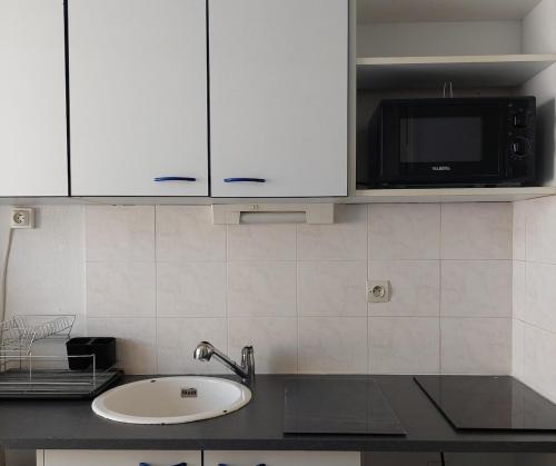 une cuisine avec un évier et un micro-ondes dans l'établissement T3 au bord de l'étang de Thau, à Balaruc-les-Bains