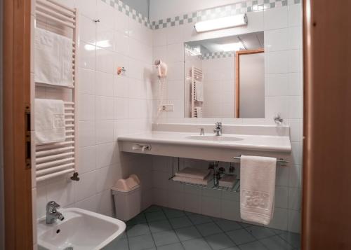 a white bathroom with a sink and a mirror at Hotel Figl ***S in Bolzano