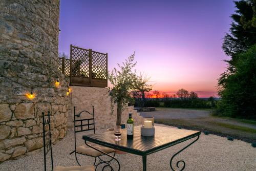 une table et des chaises sur une terrasse avec un coucher de soleil dans l'établissement Toujours Dimanche Windmill Retreat, à Loubès-Bernac