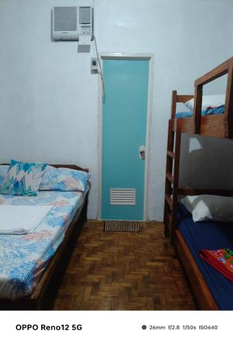 a room with two beds and a blue door at Rubilla's Homestay in Mambajao