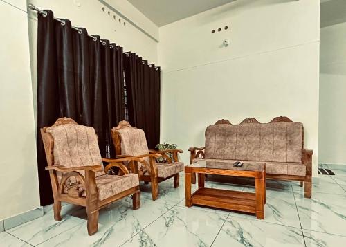 two chairs and a coffee table in a room at Skye by livNstay in Trivandrum