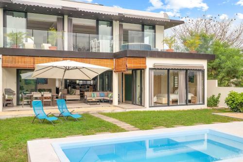 a house with a pool and two chairs and an umbrella at Sublima Villa, Luxe et élégance in La Gaulette
