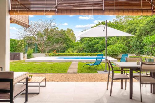 a patio with a table and an umbrella and a pool at Sublima Villa, Luxe et élégance in La Gaulette