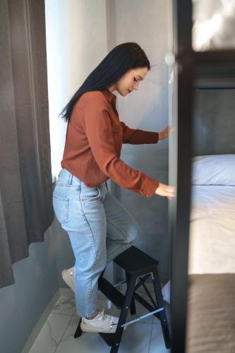 a woman standing on a stool next to a bed at Lion University & Youth Hostel Milano in Milan