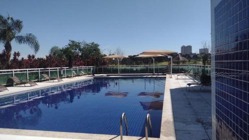 a swimming pool with chairs and umbrellas next to a building at Apartamento em frente ao novo shopping in Ribeirão Preto