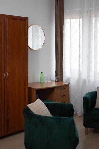 a living room with a green couch and a desk at APARTAMENTY VILLA PIGMALION - sauna, jacuzzi, parking, ogród in Kudowa-Zdrój