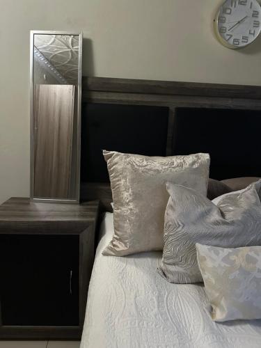 a bedroom with a bed with a mirror and pillows at The Loraine Luxury Apartments in Witbank