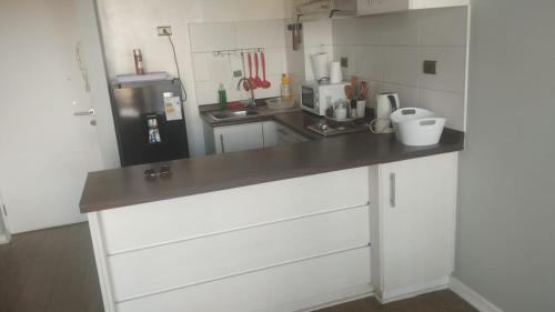 a kitchen with white cabinets and a black refrigerator at Cumbres de reñaca 922 in Viña del Mar