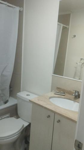 a white bathroom with a toilet and a sink at Cumbres de reñaca 922 in Viña del Mar