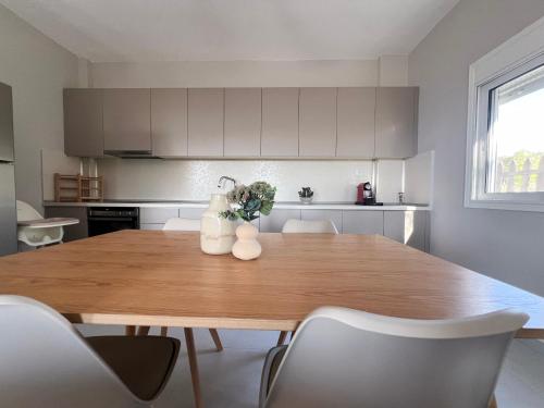 a kitchen with a wooden table and white cabinets at Casa De Vara in Nea Potidaea