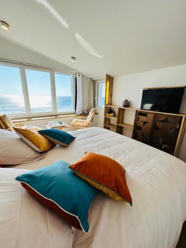 une chambre avec un grand lit avec des oreillers dessus dans l'établissement L'écume de mer, à Barneville-Carteret