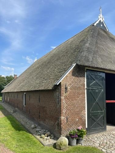 an old brick building with a large door at Rijksmonument De Heidepleats it skiep in Iniaheide