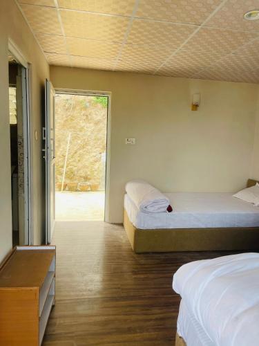 two beds in a room with a window at Nagarkot New Homestay in Nagarkot