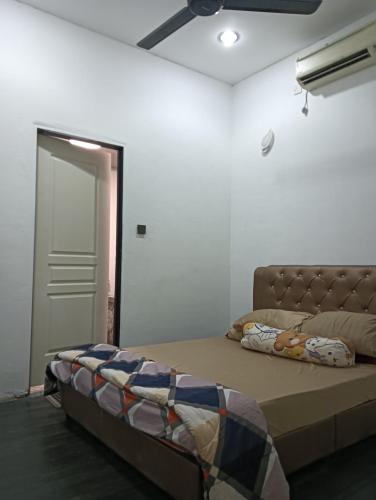 a bedroom with a bed and a ceiling fan at Laman Mesra Qaseh in Merlimau