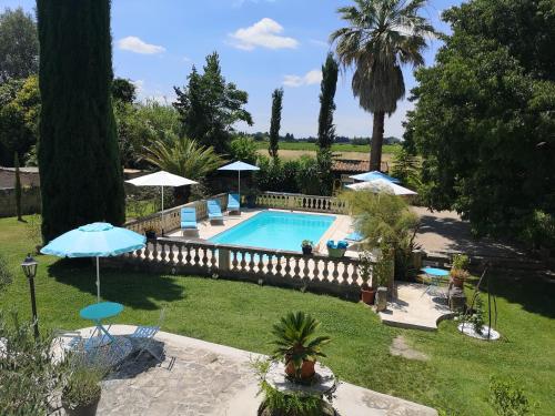 - une piscine dans une cour avec des chaises et des parasols dans l'établissement Gîte Le Mas des Agapes, à Beaucaire