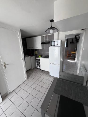 une cuisine avec des armoires blanches et un réfrigérateur blanc dans l'établissement coin tranquille, à Pont-du-Château