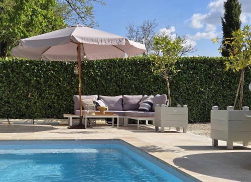 - un canapé installé sous un parasol à côté de la piscine dans l'établissement La Demeure du Bord'Ô, à Lagruère