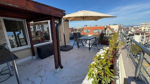 a patio with a table and an umbrella on a balcony at Apartment near Vitosha mountain, self check-in, with underground parking in Sofia