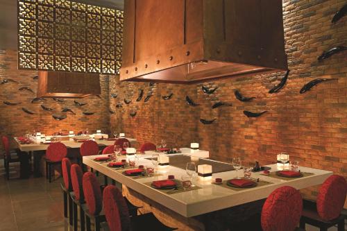 a dining room with tables and red chairs at Secrets Puerto Los Cabos Golf & Spa18+ in San José del Cabo