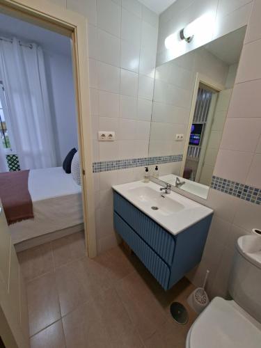 a bathroom with a sink and a toilet and a bed at Apartamento con piscina Bormujos in Bormujos