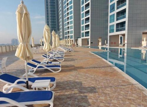 a row of lounge chairs and umbrellas next to a pool at Best place to stay by the sea in Ajman 