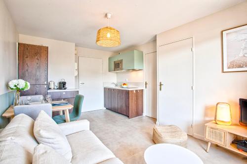 un salon avec un canapé et une cuisine dans l'établissement Appt cosy Cabourg 2 min plage 5 min thalasso, à Cabourg