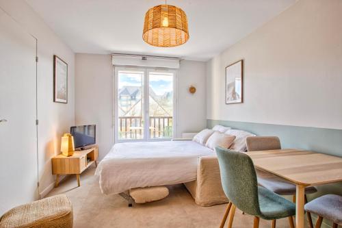 une chambre avec un lit, une table et une fenêtre dans l'établissement Appt cosy Cabourg 2 min plage 5 min thalasso, à Cabourg