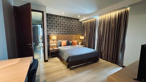 a bedroom with a bed and a desk and a mirror at The H Tower Rasuna Suites Kuningan Jakarta By Villaloka in Jakarta