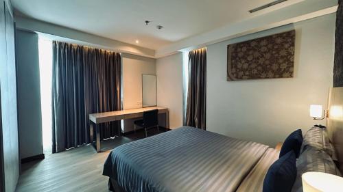 a hotel room with a bed and a desk at The H Tower Rasuna Suites Kuningan Jakarta By Villaloka in Jakarta