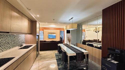 a kitchen with a dining table and a living room at The H Tower Rasuna Suites Kuningan Jakarta By Villaloka in Jakarta