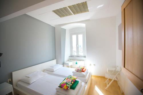 a white room with two beds and a window at Hostel Kosy in Rijeka